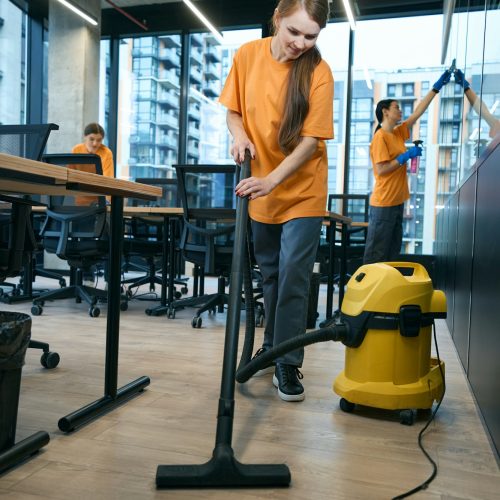 Energetic cleaning company team in uniform washes and disinfects coworking space